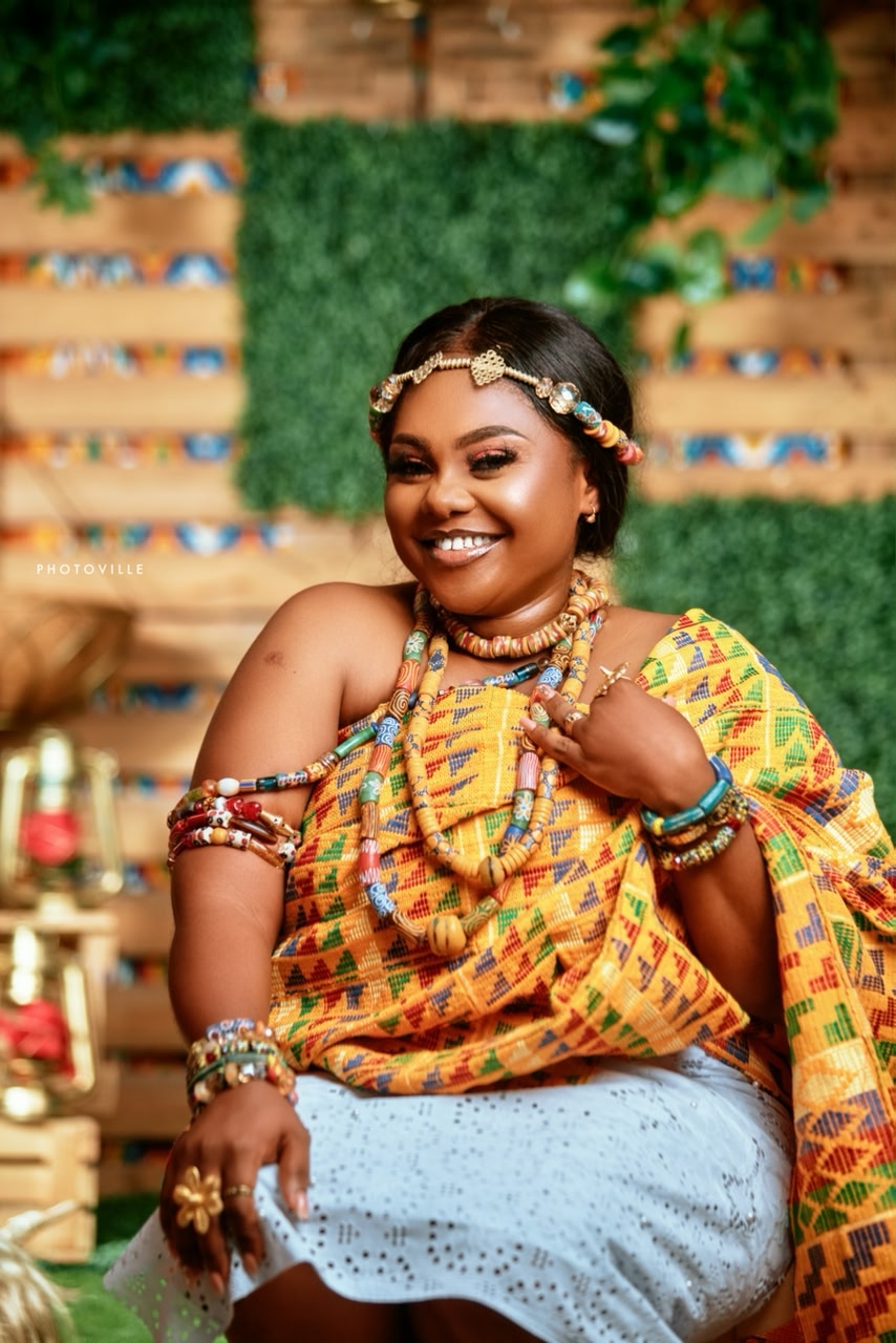 Smiling woman in kente cloth with traditional beads and gold jewellery